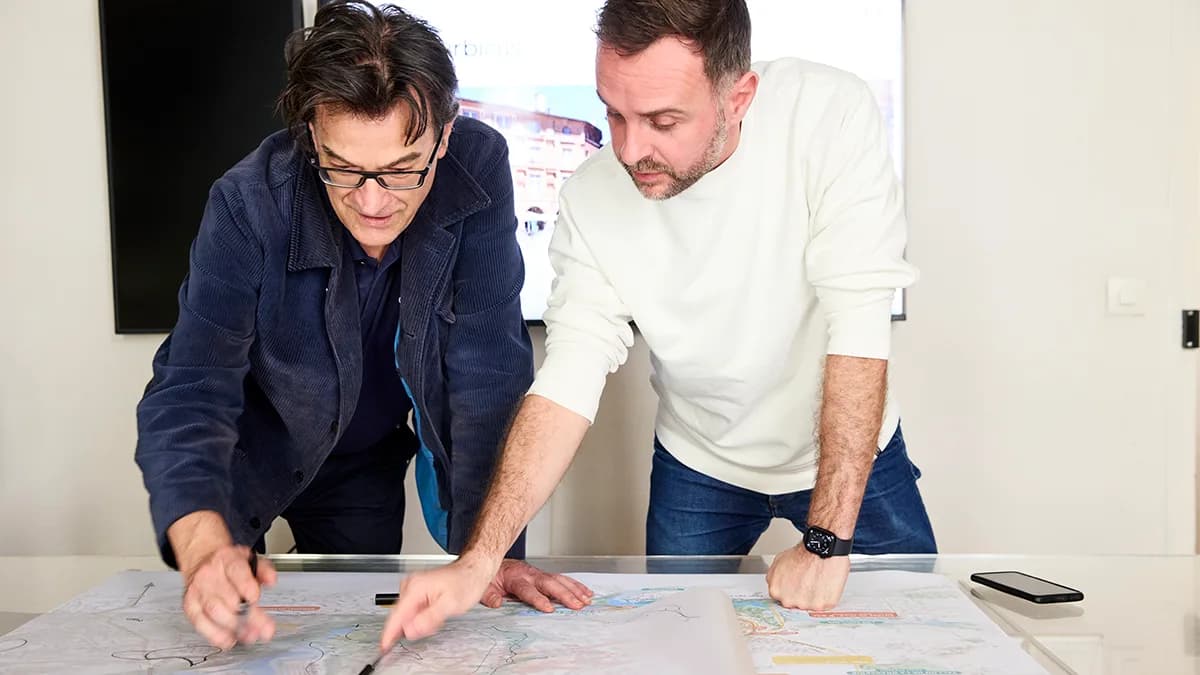 Deux dirigeants de petite entreprise annotant un plan déployé sur une table